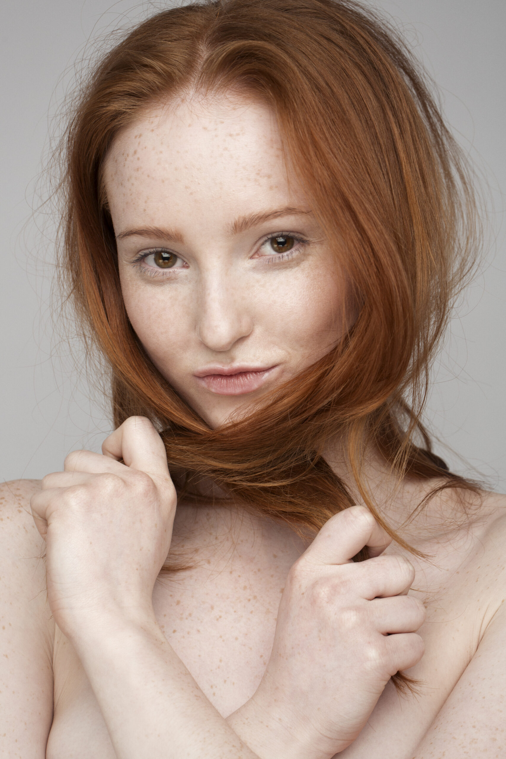 Redhead woman holding her hair with a subtle smile