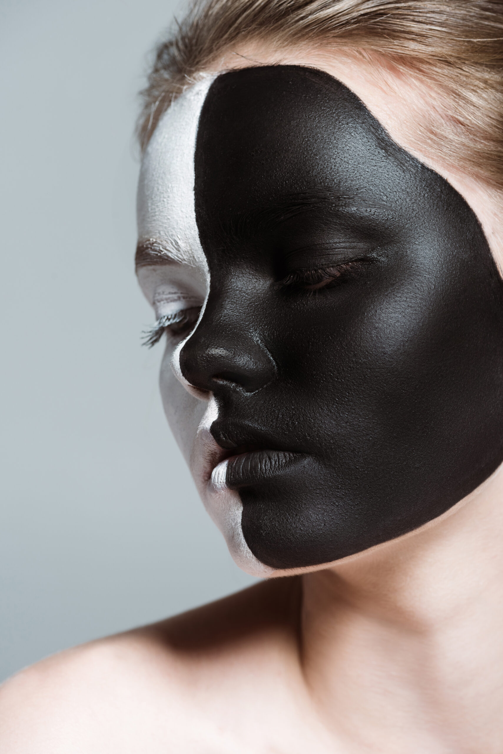 young beautiful girl with creative white and black bodyart on face, isolated on grey