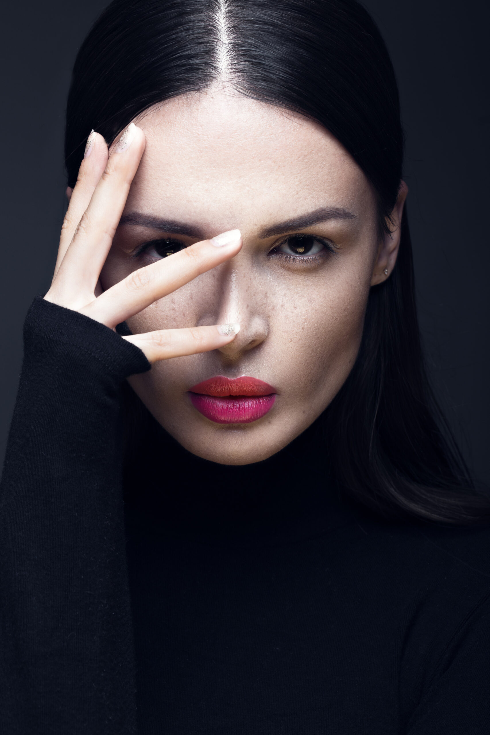 Beautiful brunette girl in a black dress, straight hair and trendy makeup. Glamour beauty face.